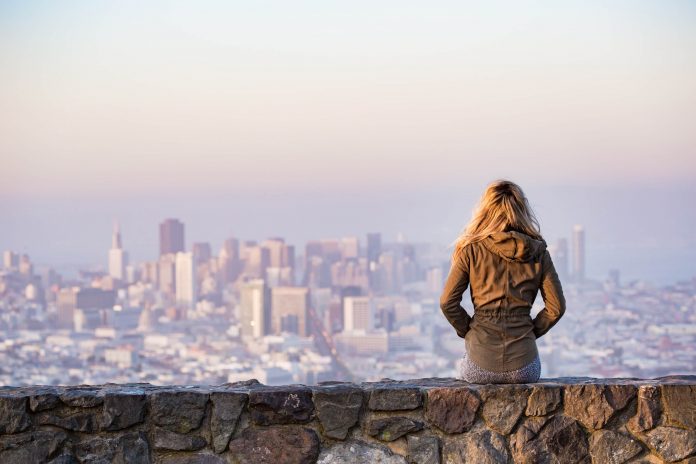 Woman-on-rock-platform-viewing-city-at-sunset-10000x15000