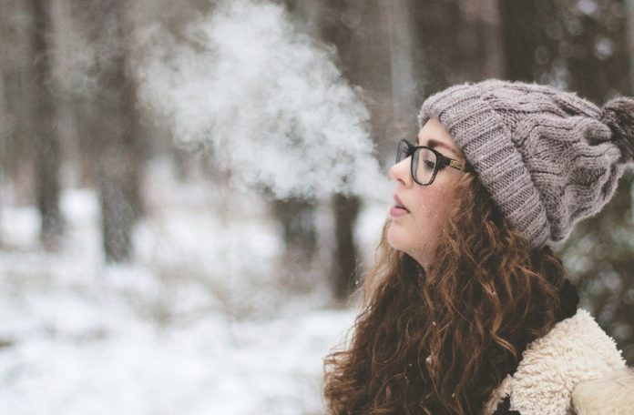woman-standing-and-smoking-on-snow-covered-forest-2182190