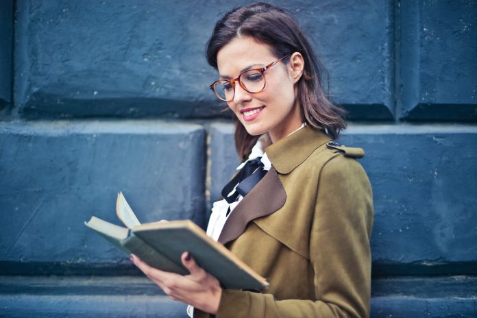woman-in-brown-suede-peacoat-reading-a-book-762080